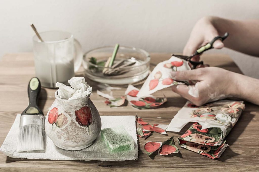 Donna che incolla ritagli di carta stampata per decoupage