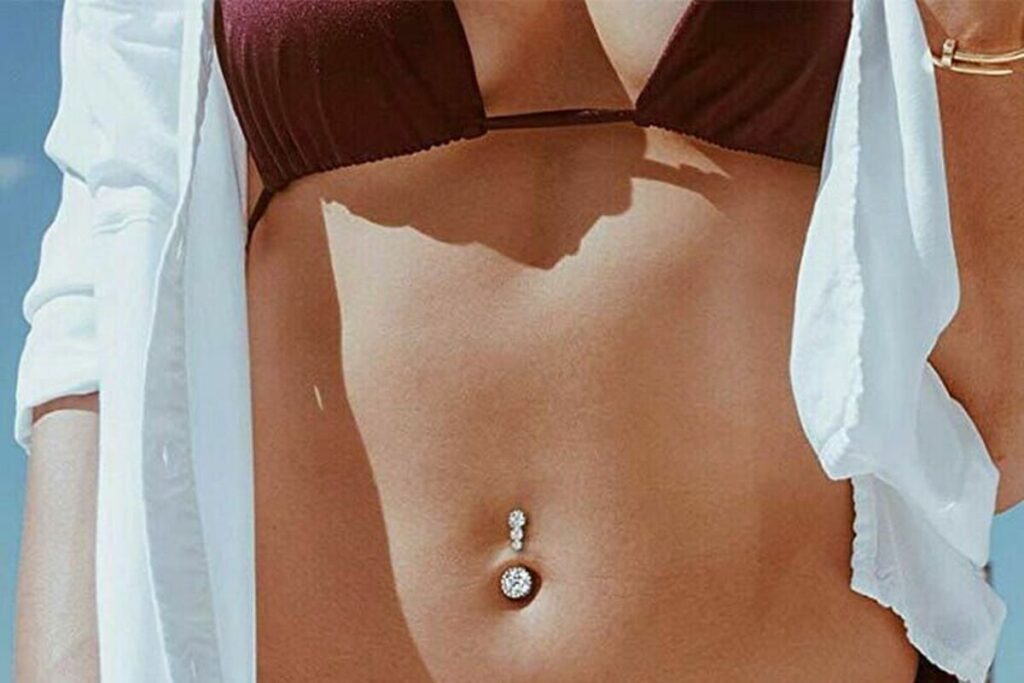 foto ragazza con piercing ombelico con strass in bikini e camicia