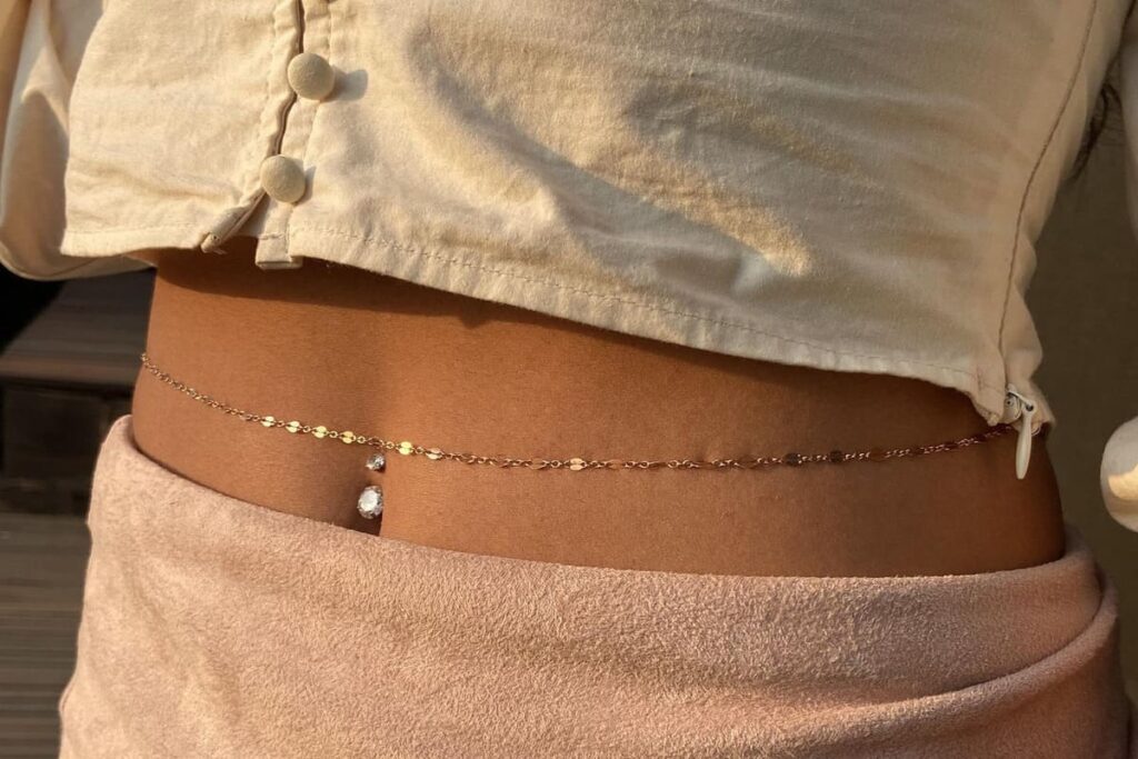 Ragazza con piercing ombelico e body chain