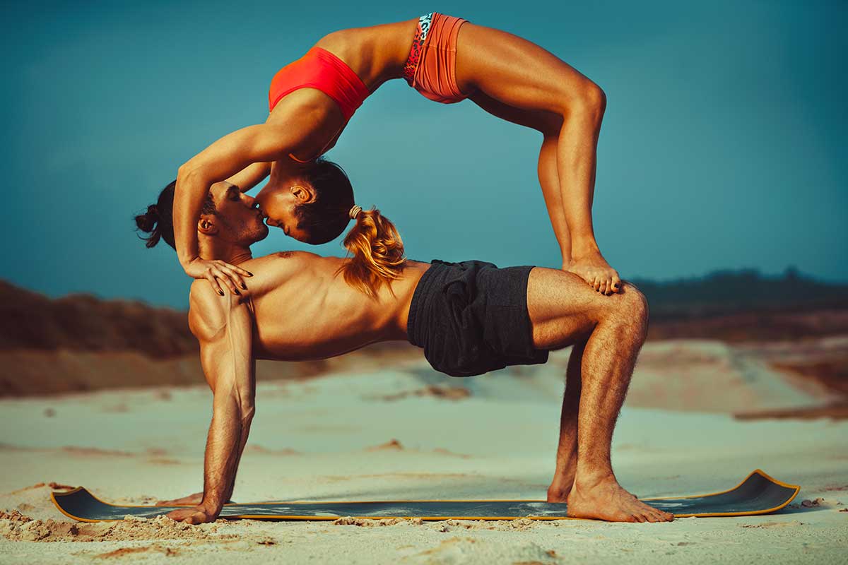 coppia fa yoga in spiaggia e si bacia