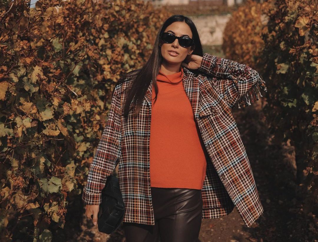 L’influencer Giulia Valentina immersa in paesaggio autunnale con indosso un dolcevita arancione