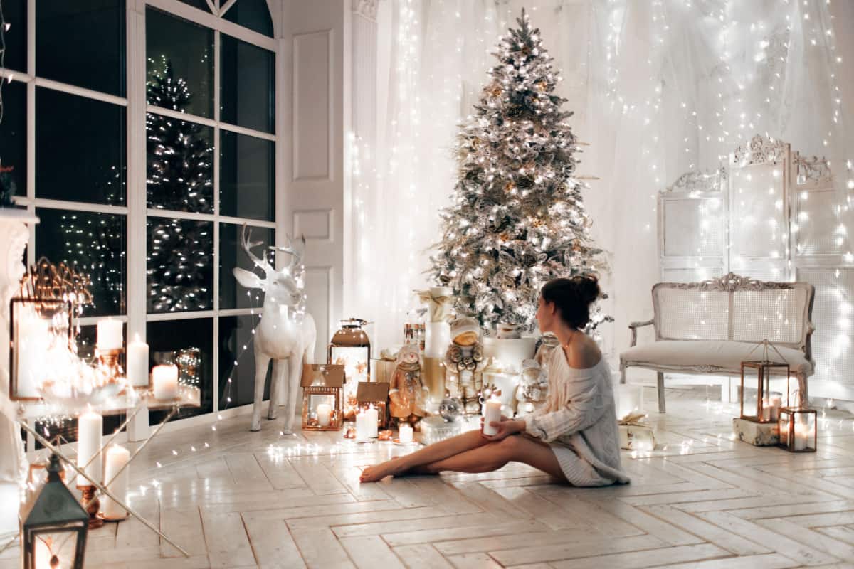 ragazza seduta a terra in un soggiorno con albero di Natale e decorazioni natalizie