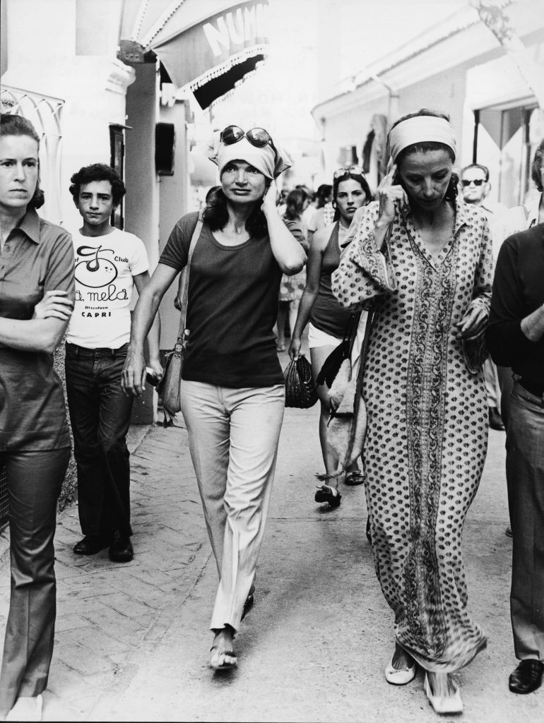 La first lady americana Jacqueline Kennedy Onassis (1929-1994) con un fazzoletto in testa cammina per una strada trafficata con le ragazze Gaines a Capri, Italia, all'inizio degli anni '70.