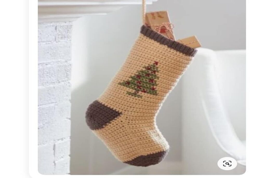 calza befana appesa realizzata all'uncinetto di colore beige e marrone, con un albero di Natale disegnato