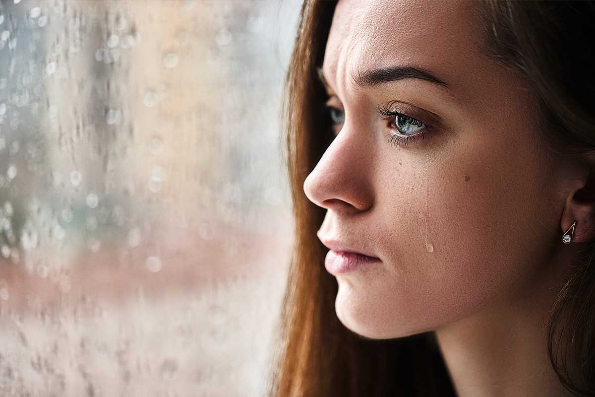 ragazza piange davanti alla finestra