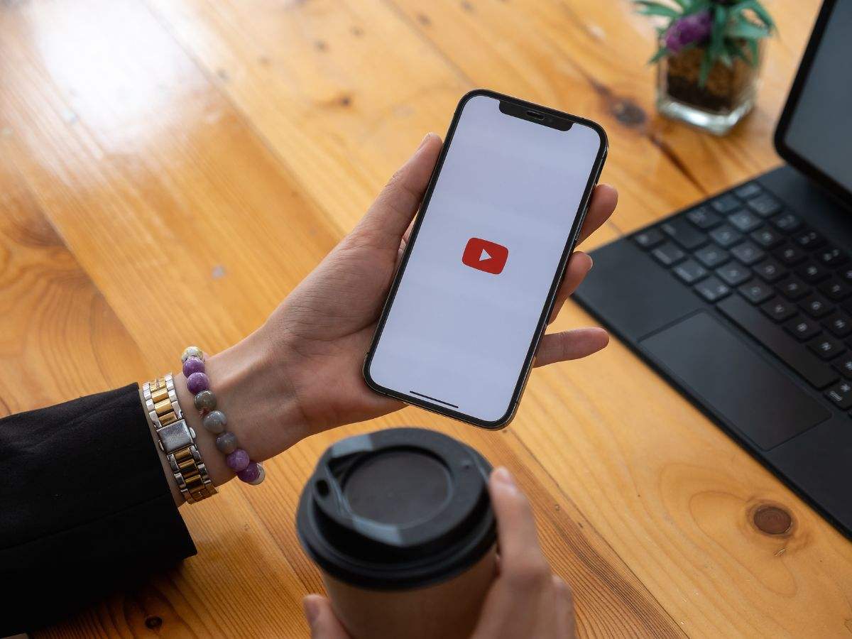 persona con smartphone in mano e logo Youtube