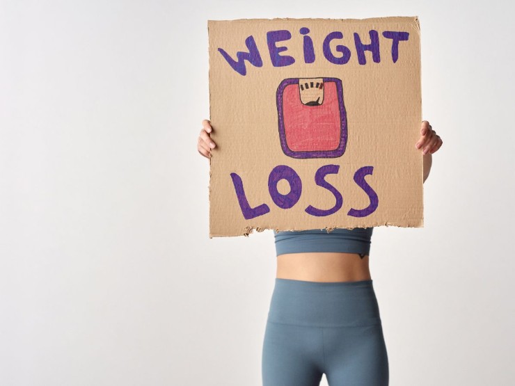ragazza con cartellone in mano con scritta "weight loss"