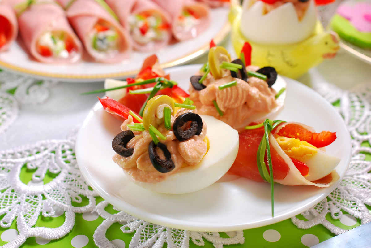 tavola imbandita con antipasti di pasqua misti come uova farcite e involtini di prosciutto cotto