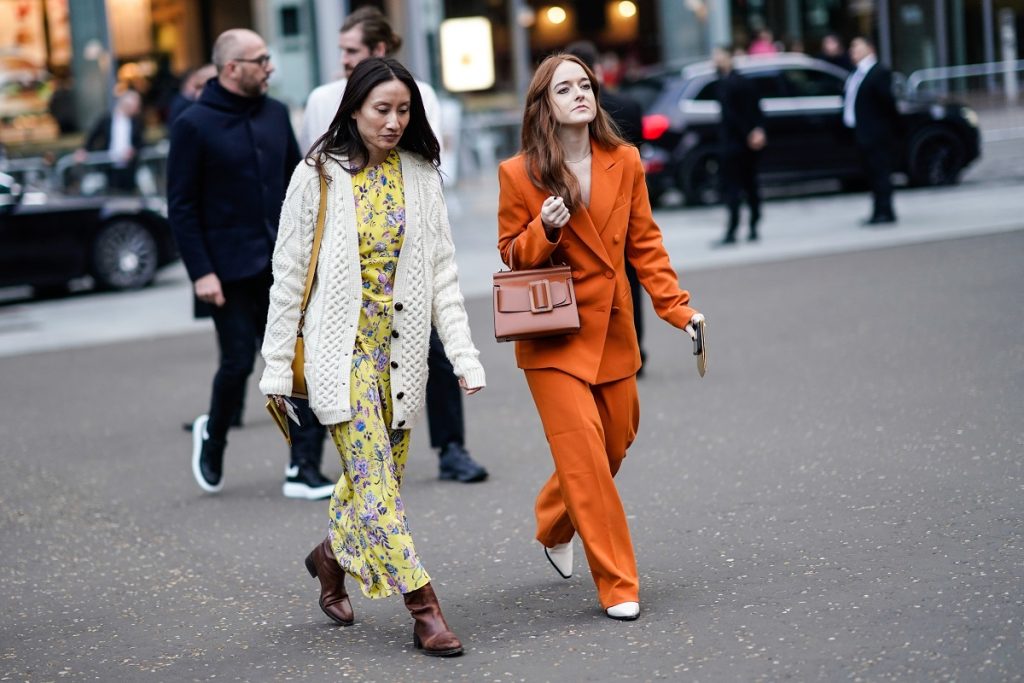 Un ospite (L) indossa una giacca di maglia bianca, un abito lungo giallo con stampa floreale, stivali marroni; un ospite (R) indossa un tailleur pantalone arancione doppiopetto con pantaloni larghi, una borsa marrone, scarpe bianche, fuori Burberry, durante la London Fashion Week febbraio 2019 il 17 febbraio 2019 a Londra, Inghilterra