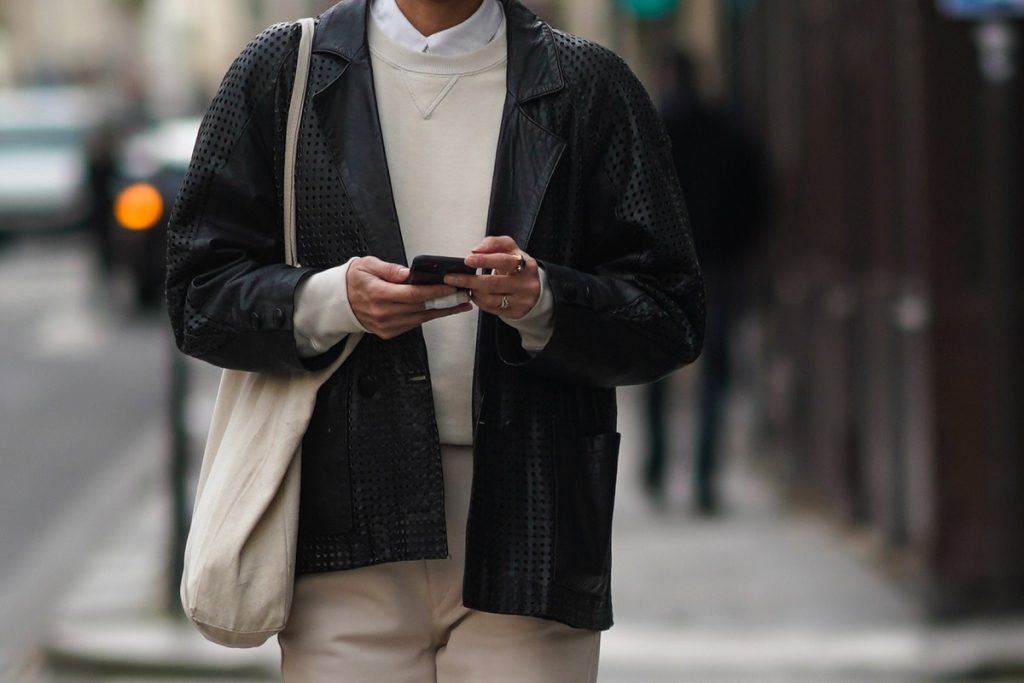 Un passante indossa una camicia bianca, un pullover bianco, una giacca in rete di pelle nera, una borsa bianca, pantaloni, il 17 febbraio 2021 a Parigi, Francia.