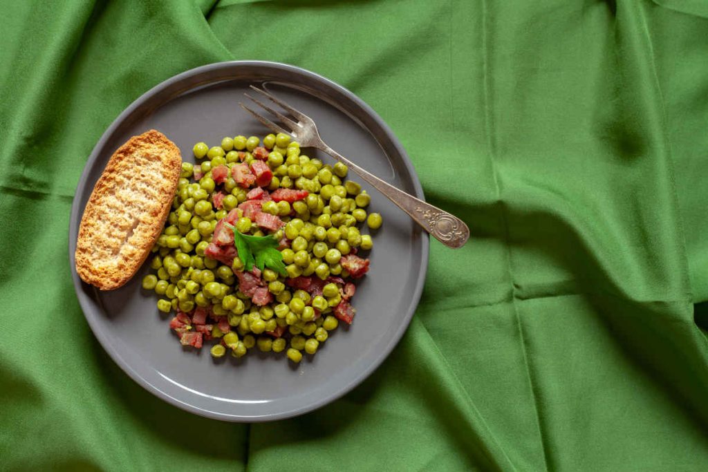 piatto grigio con contorno di piselli e pancetta a cubetti