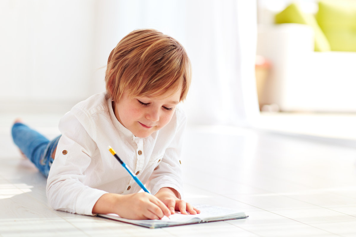 bambino sdraiato che scrive