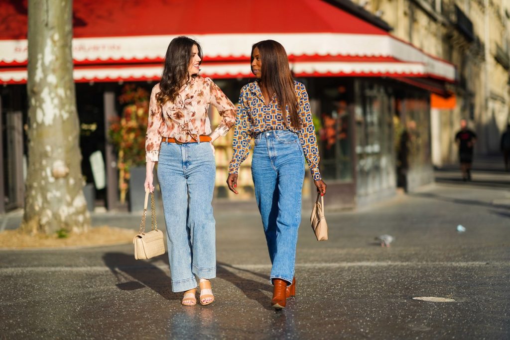 Sara Carnicella @lafillerebelle (L) indossa orecchini di APM Monaco, una camicia fluida con stampa floreale rosa e viola di Liu Jo, una cintura in pelle marrone di Mango, jeans a zampa di jeans blu di & Other Stories, una borsa Celine trapuntata beige; Dafa Traoré @poplyve indossa una maglietta colorata con motivi stampati, jeans blu denim, stivali lucidi a punta con motivo coccodrillo in pelle marrone, una borsa Prada, il 28 marzo 2021 a Parigi, Francia