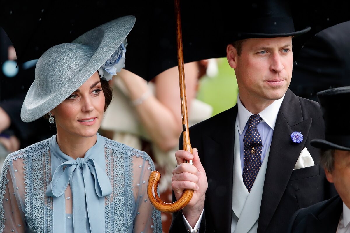 Catherine, duchessa di Cambridge e principe William, duca di Cambridge si rifugiano sotto l'ombrello mentre frequentano il primo giorno del Royal Ascot all'ippodromo di Ascot il 18 giugno 2019 ad Ascot, in Inghilterra