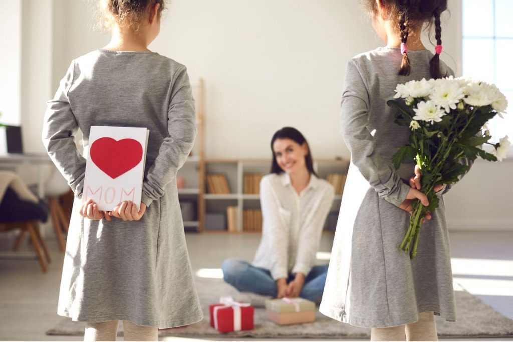 bambine regalano fiori e biglietto alla mamma per la festa della mamma