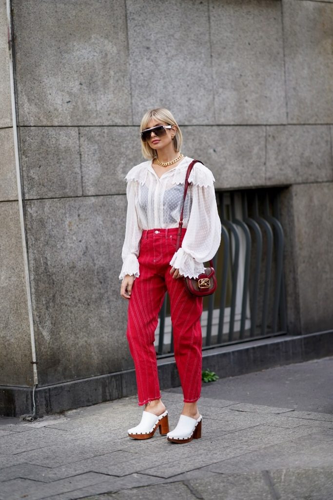 Xenia Adonts indossa occhiali da sole, una collana d'oro, una camicia bianca di pizzo a rete arruffata, pantaloni rossi, una borsa rossa, scarpe bianche, fuori Etro, durante la Milano Fashion Week Autunno / Inverno 2020-2021 il 21 febbraio 2020 a Milano, Italia