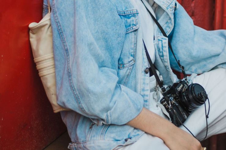 Ragazza seduta con look denim e macchina fotografica