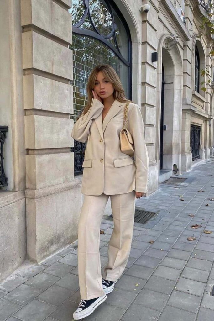 ragazza con completo pantalone e blazer beige e sneakers