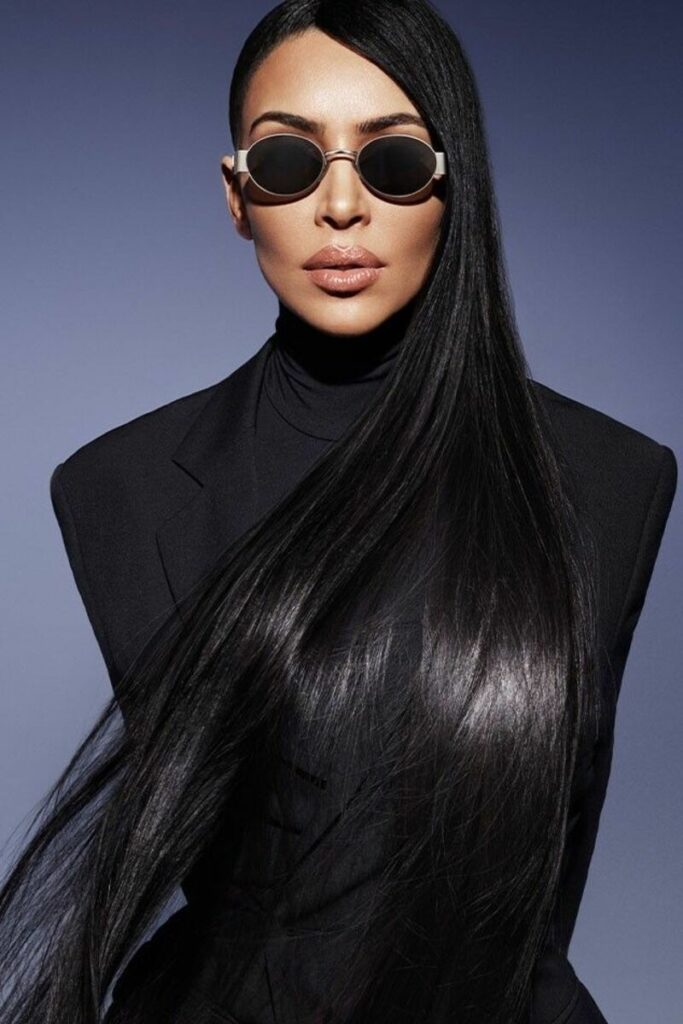 Kim Kardashian con capelli lunghissimi neri e lucenti che posa con occhiali da sole vestita di nero