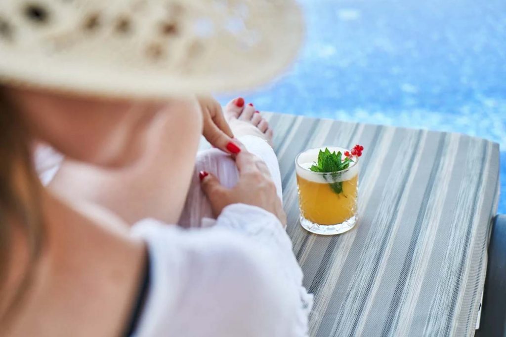 donna a bordo piscina in vacanza con cocktail