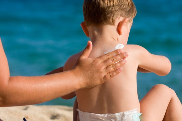 bimbo di spalle con crema solare
