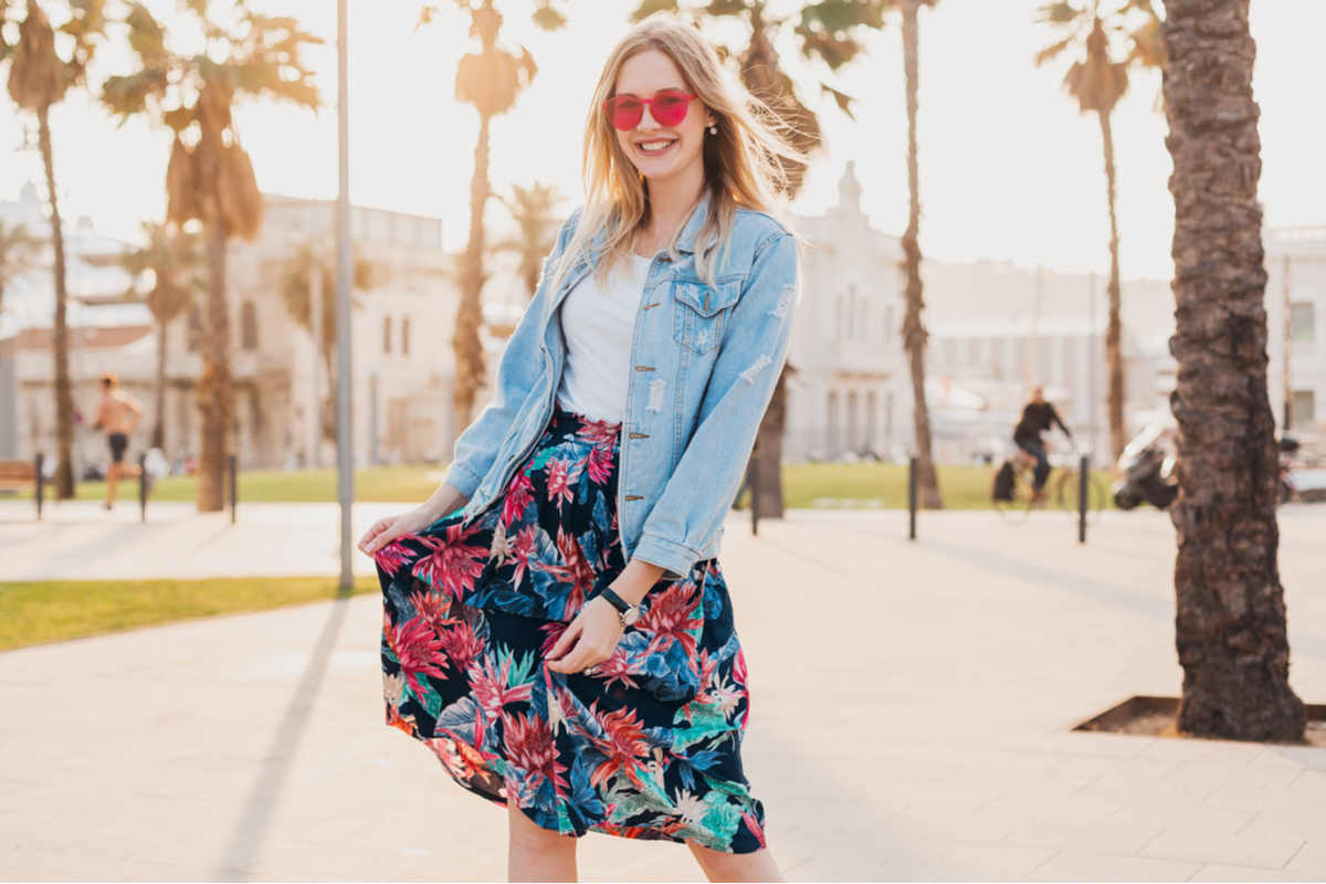 ragazza con gonna fantasia floreale, occhiali da sole e giacca denim