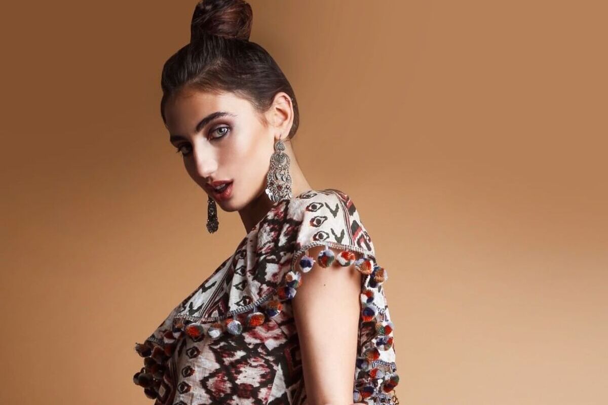 modella di profilo con chignon alto e sfondo cammello per campagna Postalmarket