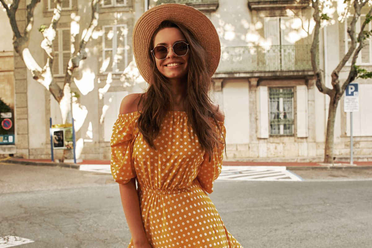ragazza con vestito giallo a pois bianchi, cappello e occhiali da sole