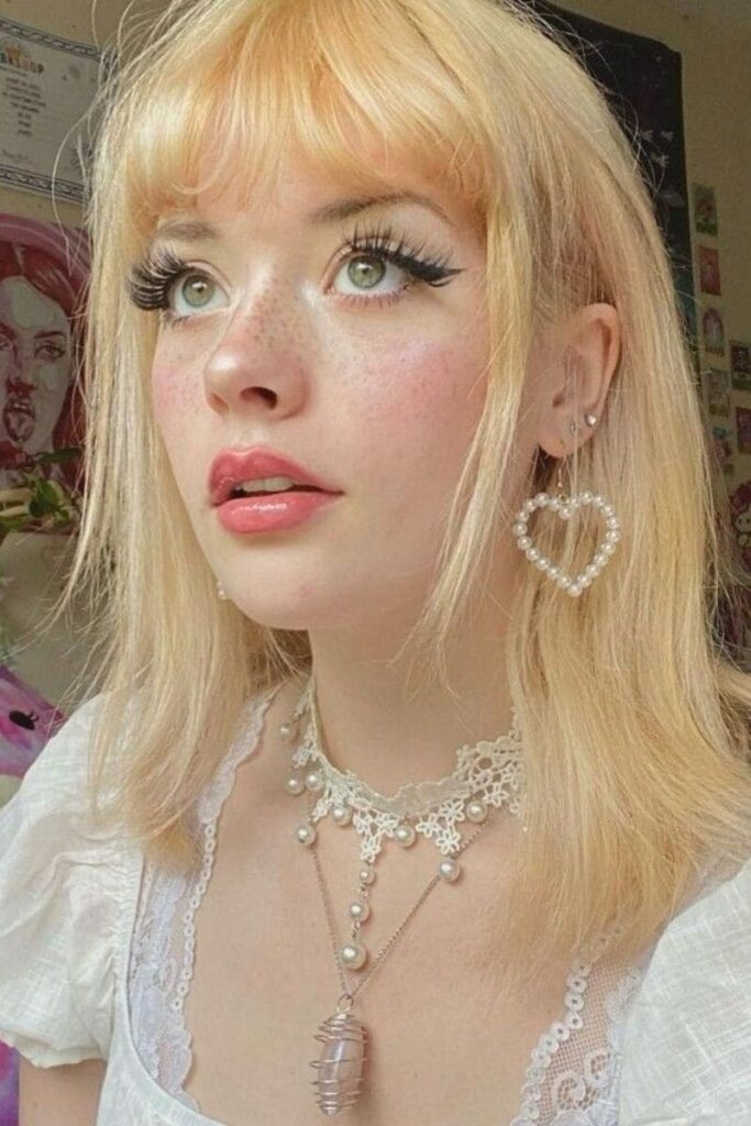 Esempio di make-up Coquette Aesthetic: ragazza con lunghe ciglia, blush e gloss rosato