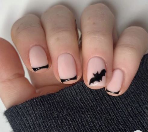 unghie di ragazza color nude con french nero e un pipistrello di colore nero sull'anulare