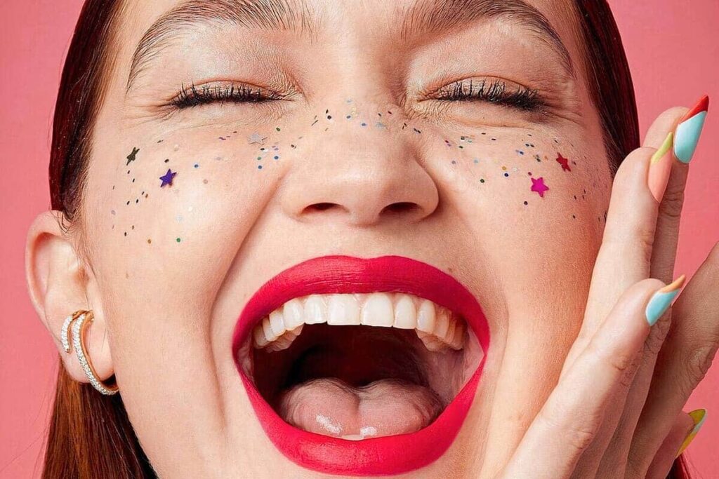 Close-up viso di Gigi Hadid con rossetto rosso e stickers viso a stellina
