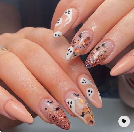 mani di una ragazza con unghie in gel con decorazioni varie, con fantasmi e con glitter