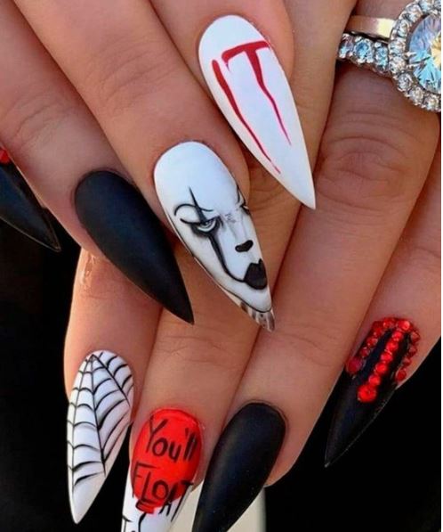 mani di ragazze con unghie a tema halloween di colore bianco, nero, rosso