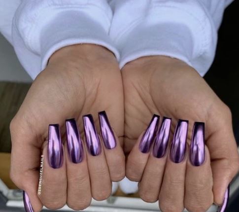 mani di ragazza con unghie lunghe di colore viola metallizzato 