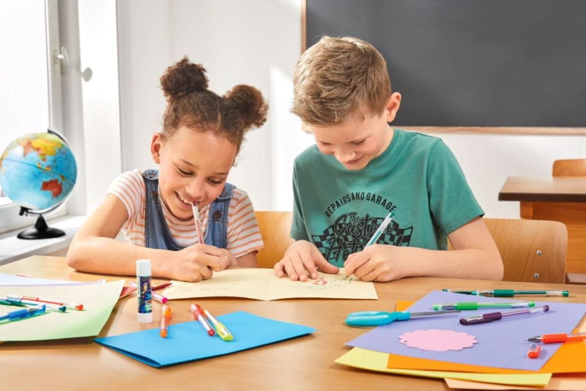 due bambini che utilizzano album e colori