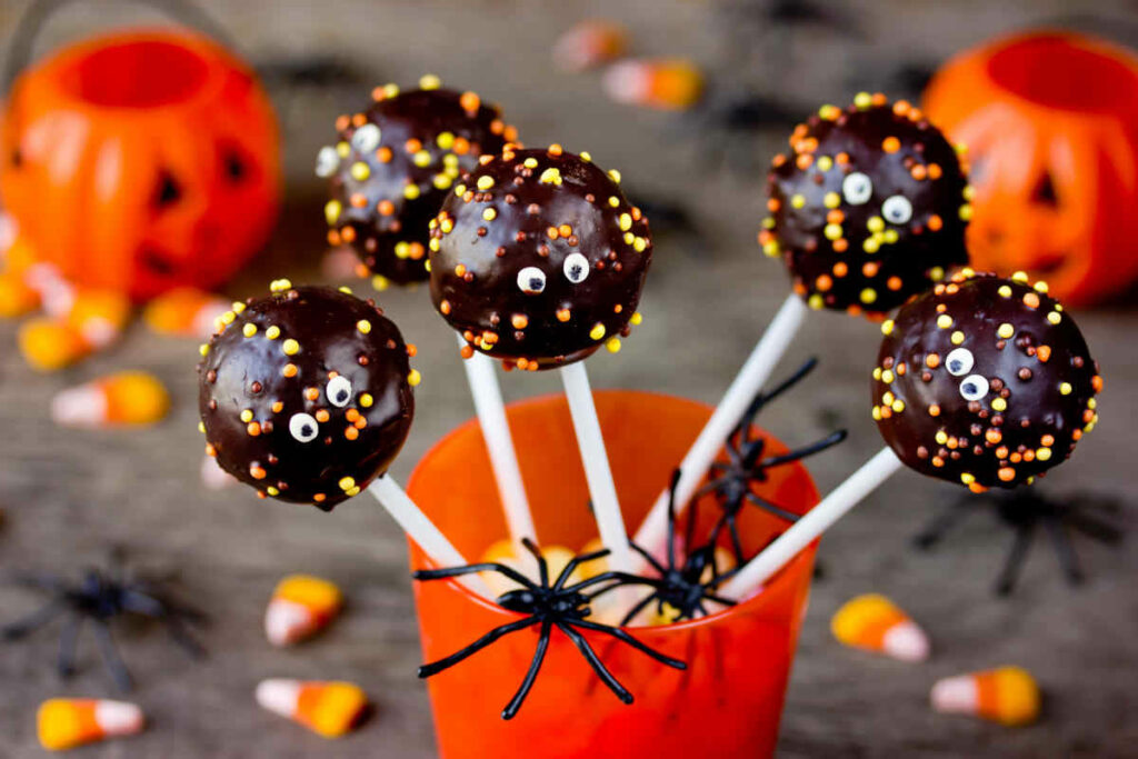 bicchiere arancione con cake pops di halloween e ragni di liquirizia