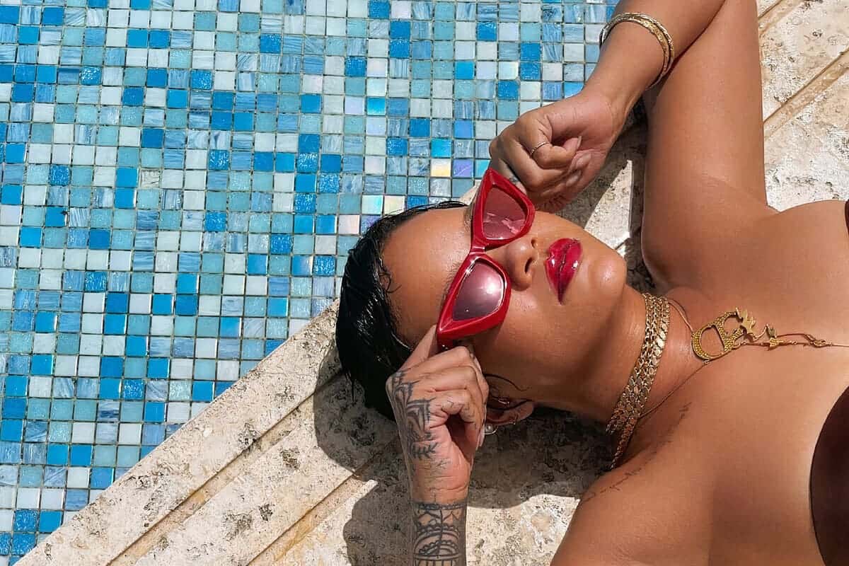 Rihanna a bordo piscina con occhiali da sole e rossetto rosso - Errori make-up da evitare con l'abbronzatura