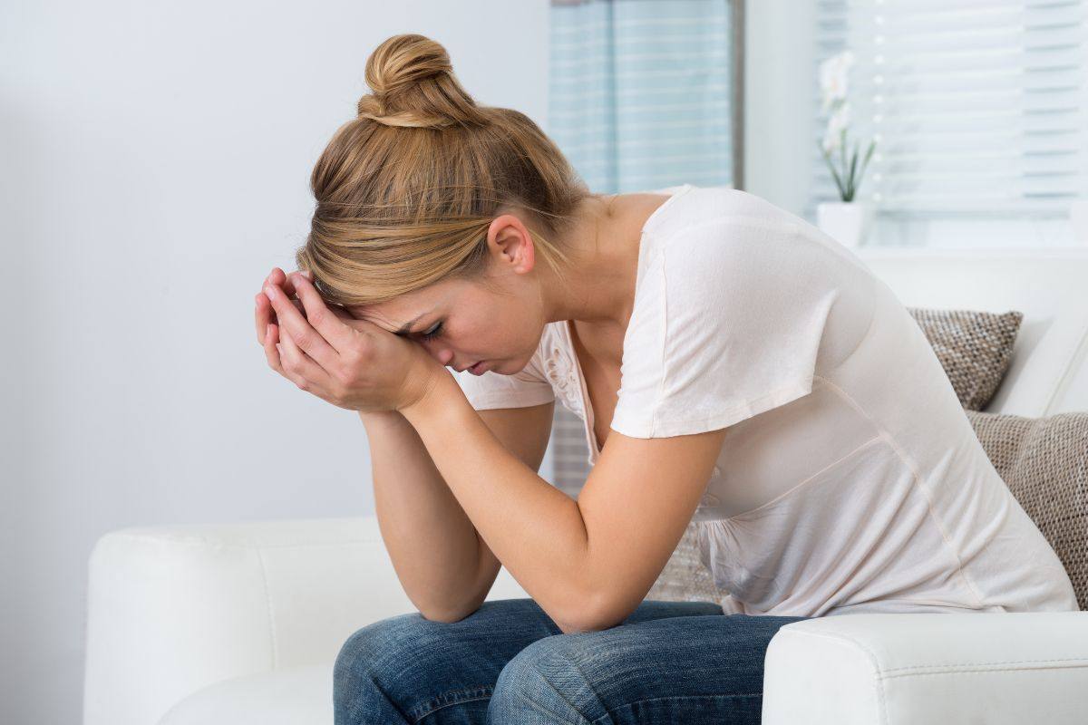 persona seduta che si tocca il viso con le mani