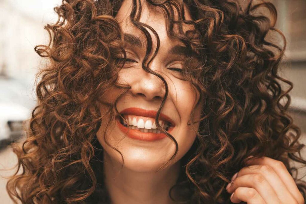 Ragazza sorridente, con capelli ricci e castani