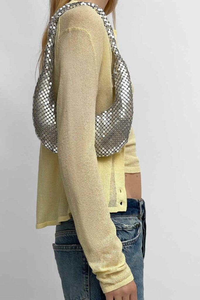 donna con borsa mezzaluna in paillettes argento e cardigan giallo