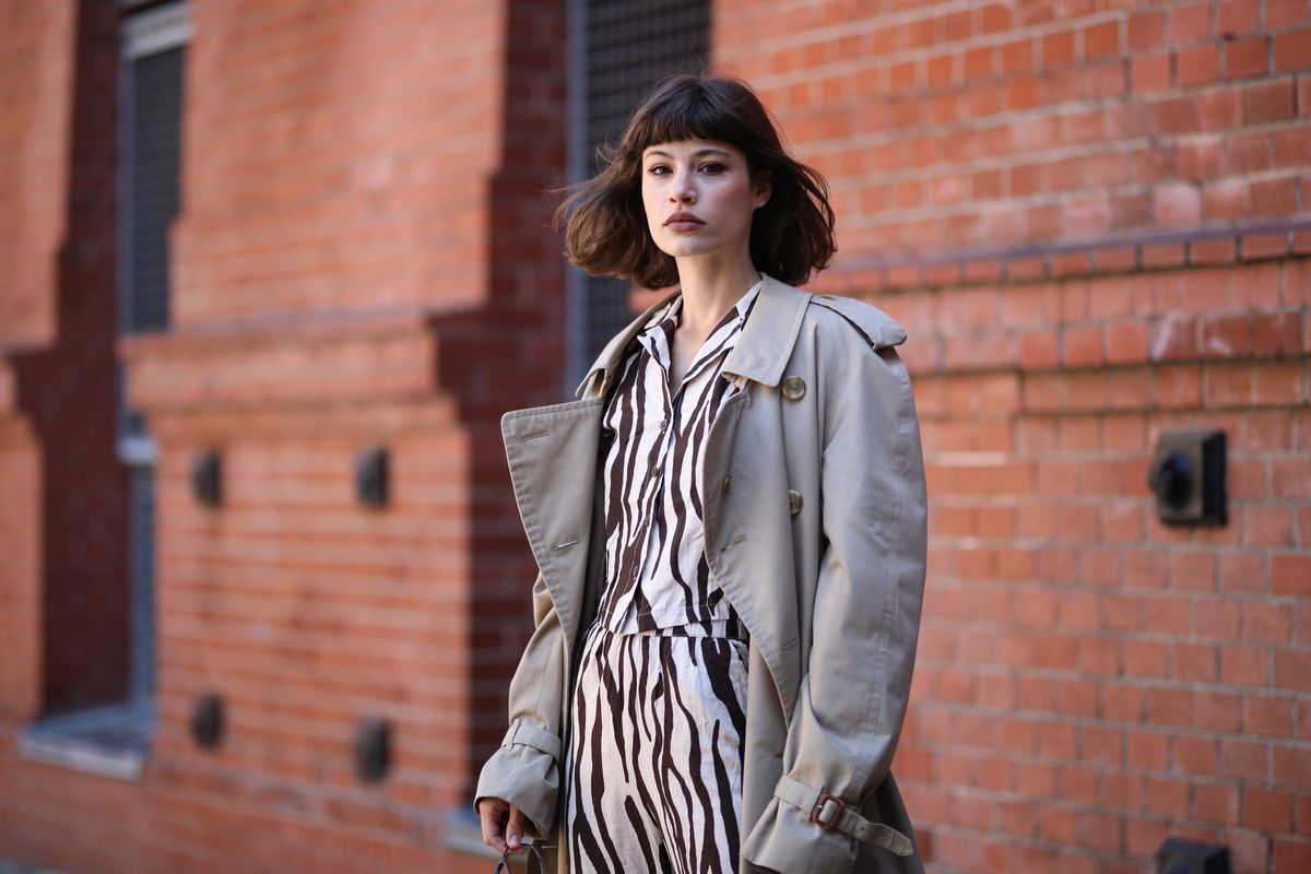 donna con trench grigio e abito zebrato bianco e nero