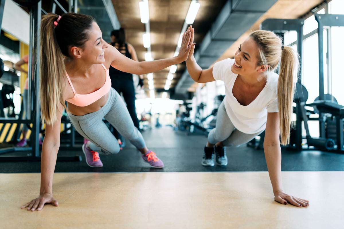 Due amiche si allenano in palestra sul tappetino