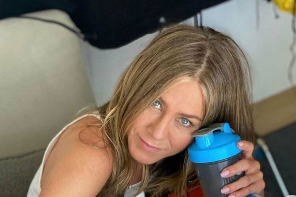 Jennifer Aniston in primo piano senza trucco con una borraccia azzurra in mano