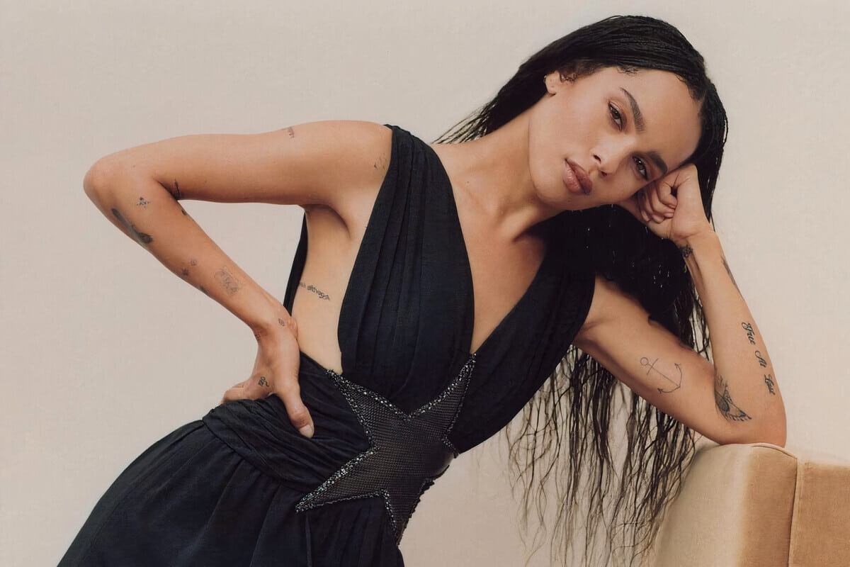 Zoe Isabella Kravitz posa con vestito elegante nero e tatuaggi sottili in bella vista - tendenza Line Art Tattoo