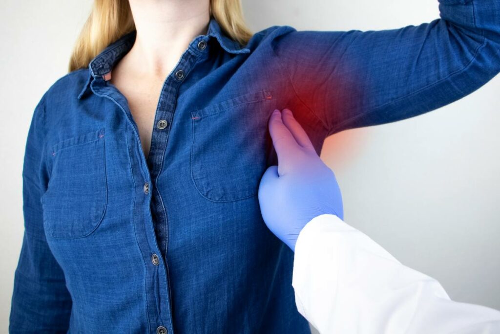 Medico che con guanto azzurro controlla l'ascella di una ragazza in camicia di jeans