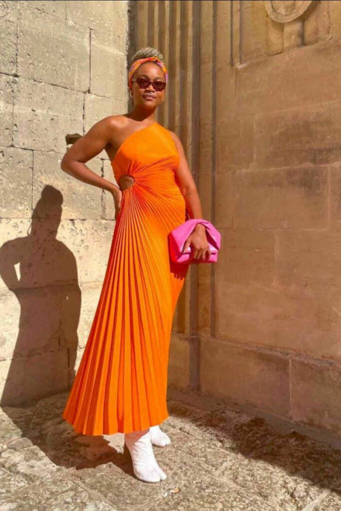 Kimberly Drew in abito arancione stivaletti bianchi e pochette fucsia