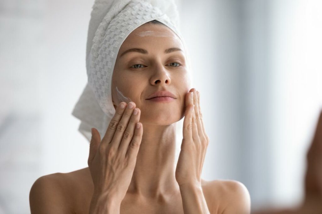 Ragazza con splendida pelle si stende la crema per il viso