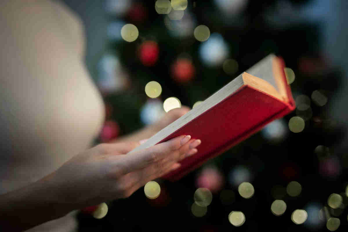 Donna che legge una poesia di Natale con albero sullo sfondo