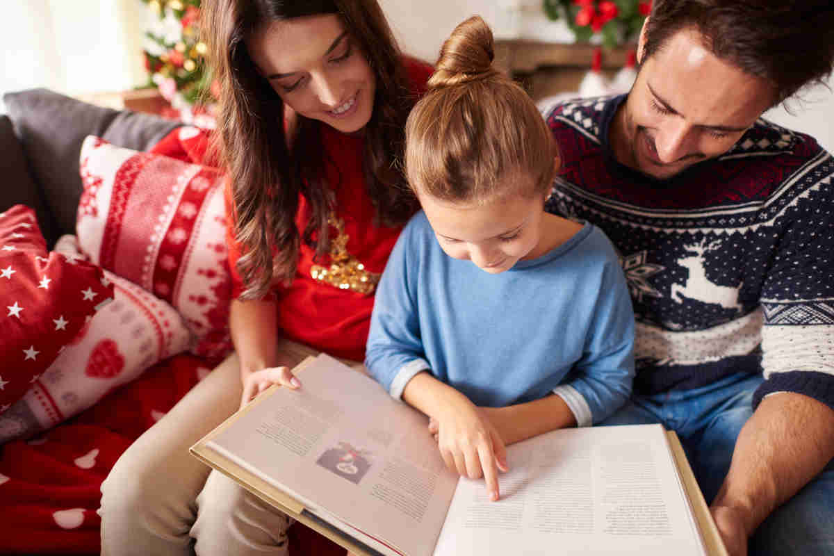 Famiglia che legge una poesia natalizia sotto l'albero