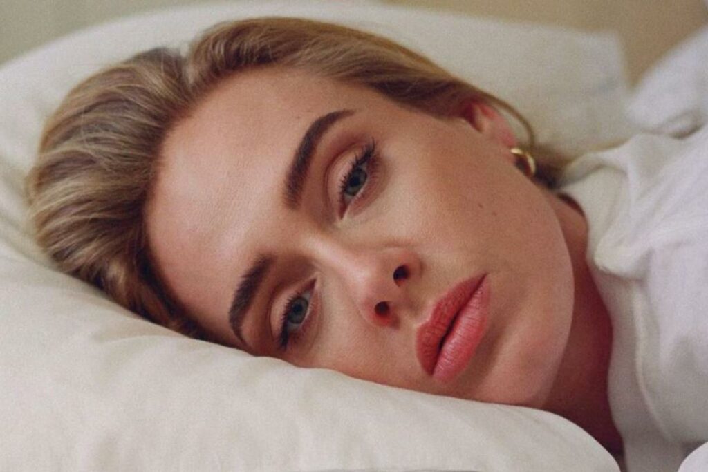 Adele poggiata sul letto senza trucco